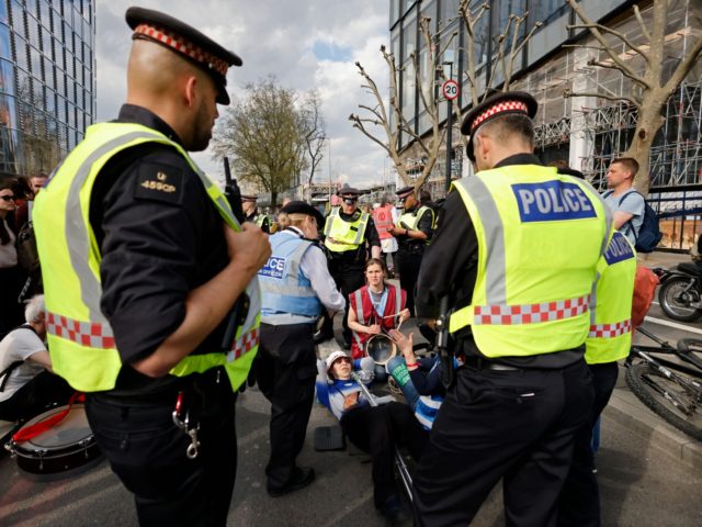 City of London police speak with activists from the climate change protest group Extinction Rebellion (XR) as they block Blackfriars Bridge in London on April 15, 2022, one of a series of actions aiming to stop the fossil fuel economy. (Photo by Tolga Akmen / AFP) (Photo by TOLGA AKMEN/AFP …