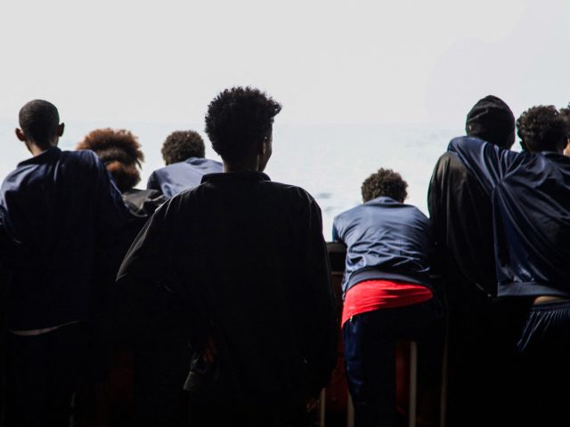 Aber an unaccompanied minor from Ethiopia (C) stands on the deck of the Geo Barents, an am