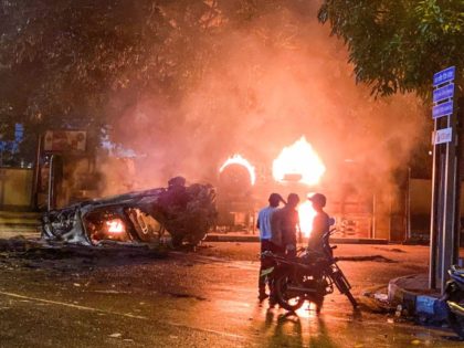 TOPSHOT - A vehicle belonging to the security personnel and a bus set alight is pictured near Sri Lanka's outgoing Prime Minister Mahinda Rajapaksa's official residence in Colombo May 9, 2022. - At least three people were killed and more than 150 wounded on May 9 in a wave of …