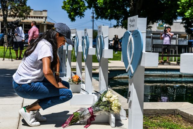 Meghan Markle, the wife of Britain's Prince Harry, places flowers as she mourns at a makeshift memorial outside Uvalde County Courthouse in Uvalde, Texas, on May 26, 2022. - Grief at the massacre of 19 children at the elementary school in Texas spilled into confrontation on May 25, as angry …