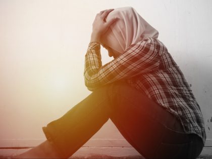 Sad unhappy lonely and depressed young Asian muslim woman crouching and crying at home. Stress exhausted feeling down expression, abused or relationship problem concept