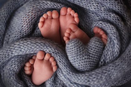 Feet of three newborn babies in a soft blanket. Heart in the legs of newborn triplets. Stu