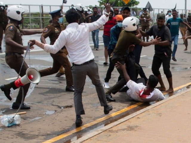 COLOMBO, SRI LANKA - MAY 09: Police officer tries to escape pro-government protester while anti-government protesters beaten during a clash on May 09, 2022 in Colombo, Sri Lanka. Sri Lankan President Gotabaya Rajapaksa has declared a state of emergency following escalating anti-government protests. Supporters of Sri Lanka’s ruling party have stormed a major protest site in Colombo, attacking anti-government demonstrators and clashing with police. Dozens of protesters have been injured. (Photo by Buddhika Weerasinghe/Getty Images)