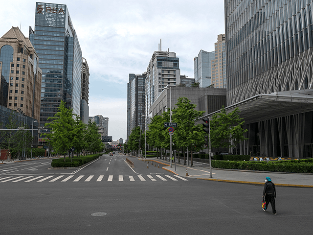 A woman crosses a nearly empty road in the Central Business District days after the local government issued a work from home directive in an effort to contain a COVID-19 outbreak on May 12, 2022 in Beijing, China. China is trying to contain a spike in coronavirus cases in the …
