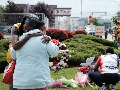 BUFFALO, NEW YORK - MAY 20: People embrace near a memorial for the shooting victims outside of Tops grocery store on May 20, 2022 in Buffalo, New York. 18-year-old Payton Gendron is accused of the mass shooting that killed 10 people at the Tops grocery store on the east side …