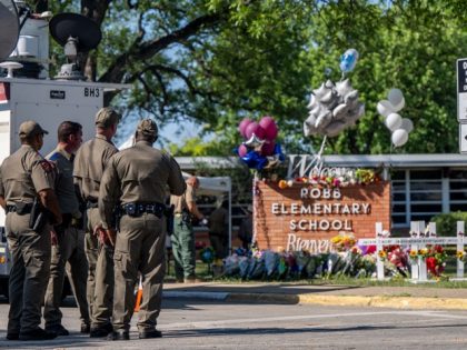 UVALDE, TEXAS - MAY 26: Law enforcement officers stand looking at a memorial following a mass shooting at Robb Elementary School on May 26, 2022 in Uvalde, Texas. According to reports, 19 students and 2 adults were killed, with the gunman fatally shot by law enforcement. (Photo by Brandon Bell/Getty …