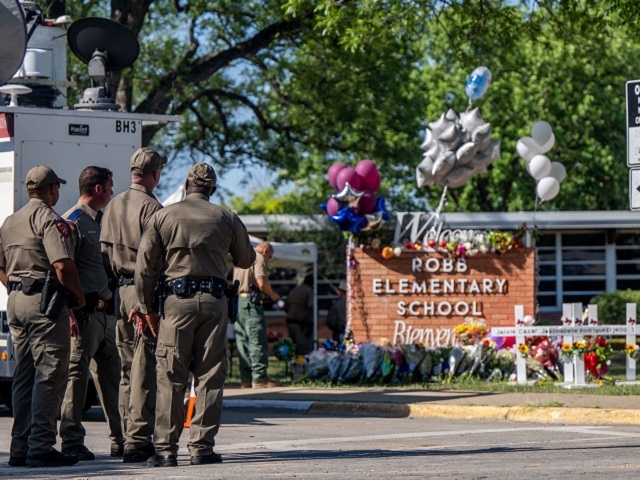 UVALDE, TEXAS - MAY 26: Law enforcement officers stand looking at a memorial following a mass shooting at Robb Elementary School on May 26, 2022 in Uvalde, Texas. According to reports, 19 students and 2 adults were killed, with the gunman fatally shot by law enforcement. (Photo by Brandon Bell/Getty Images)