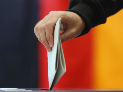 BERLIN, GERMANY - SEPTEMBER 22: A voter casts his ballot in German federal elections as a German flag hangs behind on September 22, 2013 in Berlin, Germany. Germany is holding federal elections that will determine whether current Chancellor Angela Merkel of the German Christian Democrats (CDU) will remain for a …