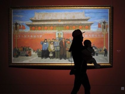 TOPSHOT - A woman carrying a baby visits an exhibition at the China National Art Museum in