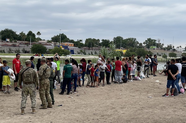 Texas National Guard soldiers assist in the detention of migrants in Eagle Pass while they wait for Border Patrol transportation vehicles. (Whether Title 42 ends or not, migrants say they are tired of waiting and surged across the Rio Grande into the Eagle Pass, Texas, area of operations. (Randy Clark/Breitbart Texas)