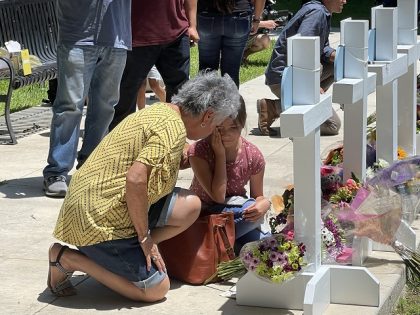 A woman comforts a young girl at the memorial near Robb Elementary School following the shooting deaths of 19 children and 2 teachers. (Randy Clark/Breitbart Texas)