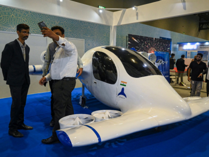 People take selfie next to India's first flying electric taxi "ePlane e200" at the "Bharat Drone Mahotsav 2022" drone show in New Delhi on May 27, 2022. (Photo by Prakash SINGH / AFP) (Photo by PRAKASH SINGH/AFP via Getty Images)