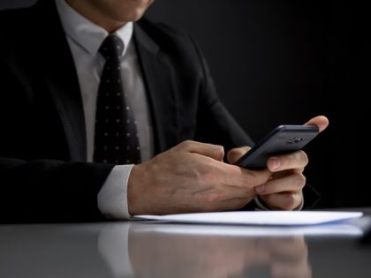 Man in suit using cell phone secretively