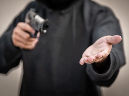 Robber points gun and demands victim hand over goods.