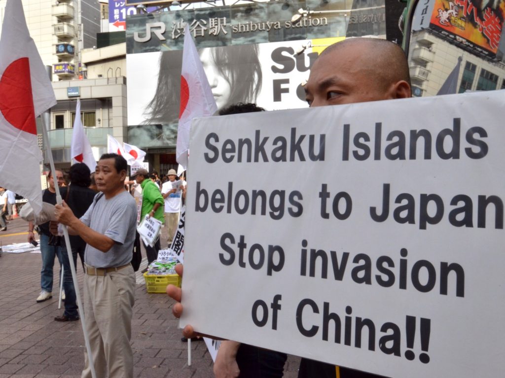 Japanese nationalists carry national flags and placards during a rally over the Senkaku islands issue, known as the Diaoyu islands in China, in Tokyo on September 18, 2012. Two Japanese activists landed on an island at the centre of a bitter dispute with China on September 18, the government in Tokyo said, as fresh anti-Japanese protests rocked Chinese cities. AFP PHOTO / Yoshikazu TSUNO (Photo credit should read YOSHIKAZU TSUNO/AFP/GettyImages)