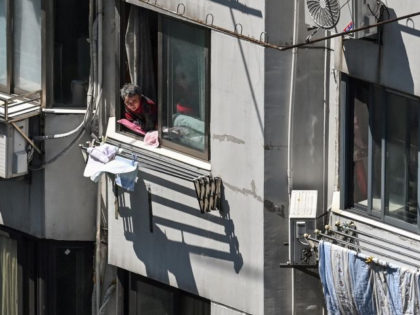 A resident looks out at the street from their window during the Covid-19 coronavirus lockdown in the Jing'an district in Shanghai on May 5, 2022. (Photo by HECTOR RETAMAL / AFP) (Photo by HECTOR RETAMAL/AFP via Getty Images)
