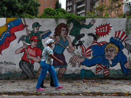 A woman walks in front of a graffiti depicting US Uncle Sam in Caracas on May 26, 2022. - The United States will not invite representatives of Venezuelan President Nicolas Maduro or Nicaragua at the Summit of the Americas next month in Los Angeles, an official Thursday. (Photo by Federico …
