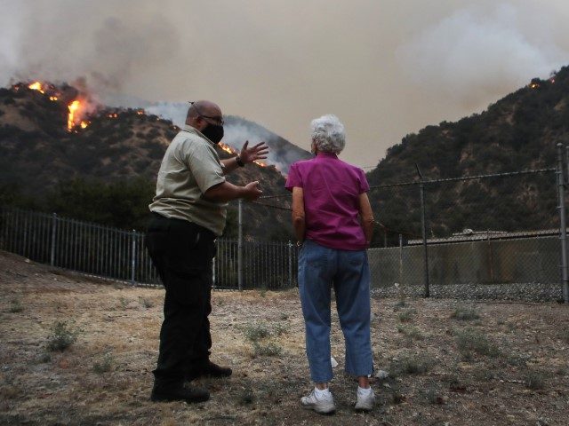 MONROVIA, CALIFORNIA - SEPTEMBER 15: U.S. Forest Service PIO Larry Smith (L), who is based out of Gila National Forest, New Mexico, briefs a local resident on the Bobcat Fire on September 15, 2020 in Monrovia, California. California's national forests remain closed due to wildfires which have already incinerated a …