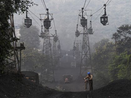 TOPSHOT - A worker pushes his bicycle under a line of cable trolleys transporting coal in Sonbhadra, Uttar Pradesh, on November 19, 2021. (Photo by Money SHARMA / AFP) (Photo by MONEY SHARMA/AFP via Getty Images)