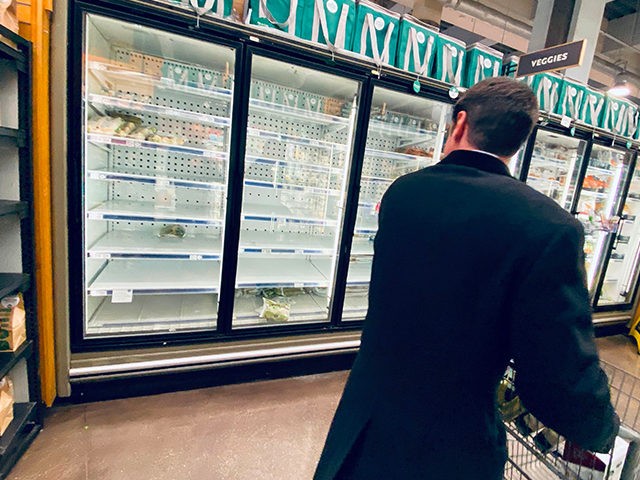 A shopper looks at empty shelves of frozen food in a downtown supermarket on March 11, 202