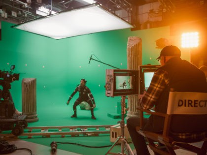 In the Big Film Studio Professional Crew Shooting Blockbuster Movie. Director Commands Cameraman to Start shooting Green Screen CGI Scene with Actor Wearing Motion Capture Suit and Head Rig - stock photo
