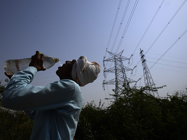 A workers quenches his thirst next to power lines as a heatwave continues to lashes the ca