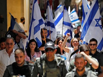 Members of Israeli security accompany Israelis lifting their national flag in Jerusalem's Old City as they mark Jerusalem Day, on May 29, 2022. - Jerusalem is bracing for a controversial "flag march" by Israelis that has sparked warnings of a new escalation from Palestinian factions. (Photo by Ahmad GHARABLI / …