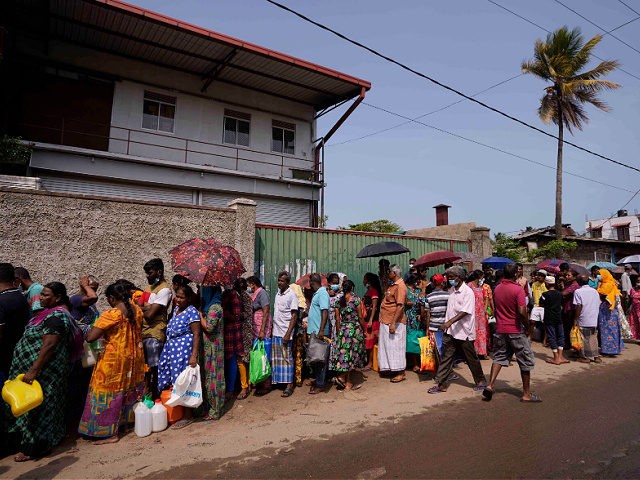 Sri Lankans wait in a queue to buy kerosene oil for cooking outside a fuel station in Colo