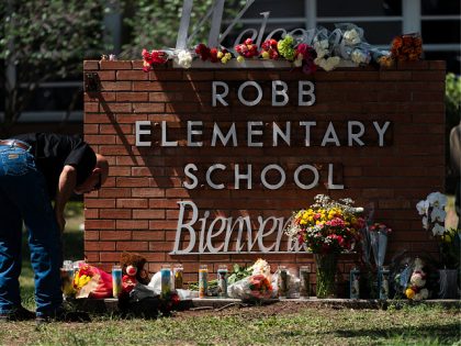 A law enforcement personnel lights a candle outside Robb Elementary School in Uvalde, Texa