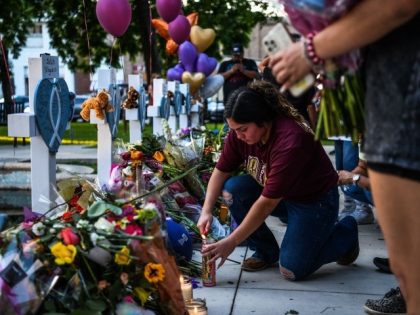 TOPSHOT - A woman lights a candle at a makeshift memorial outside Uvalde County Courthouse