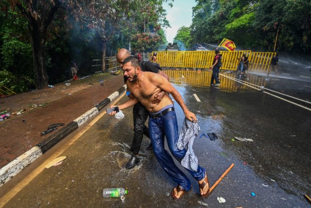 A demonstrator helps another as police use tear gas and water cannon to disperse students