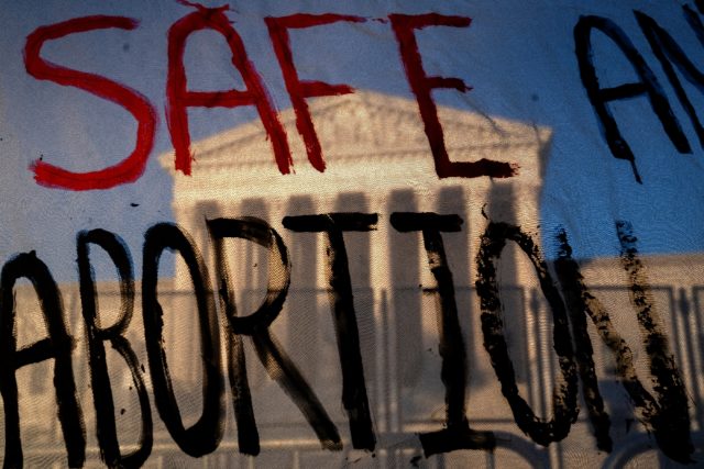 The US Supreme Court is seen through a banner reading 'Safe Abortion' in Washington on May
