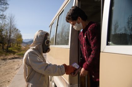 An official in protective gear checks the body temperature of a traveller on a bus as part of preventative measures against Covid-19 in Kangwon province, North Korea