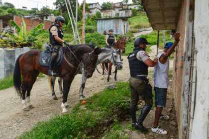 A mounted police officer frisks a man during a patrol in Cerro Las Cabras, Duran municipality, Ecuador, on April 26, 2022