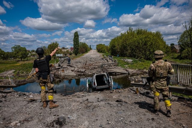 Soldiers of the Kraken Ukrainian special forces unit talk to a man at a destroyed bridge n