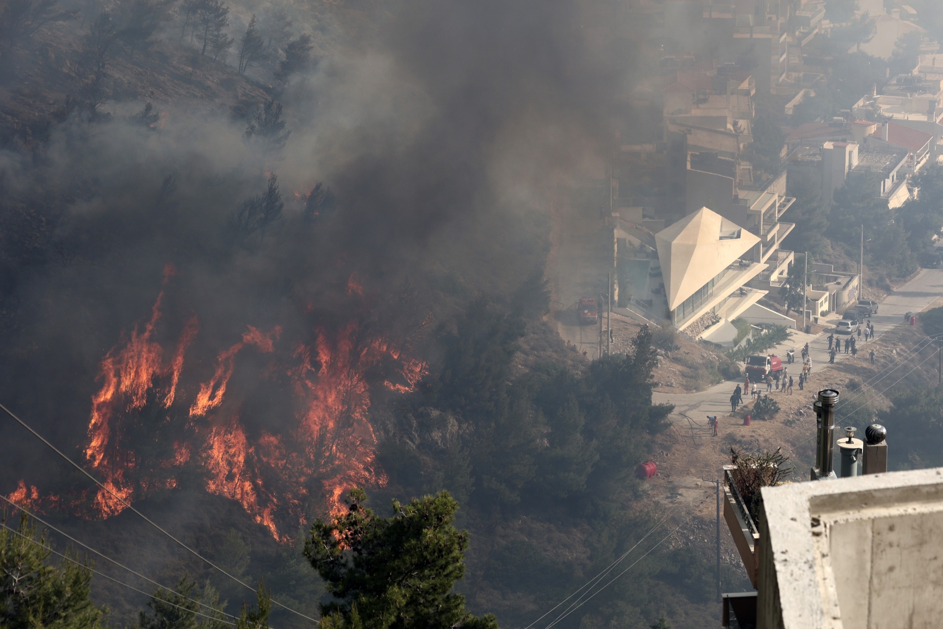 Flames burn trees on a hill as people look on during a wildfire in Voula suburb, in southern Athens, Greece, Saturday, June 4, 2022. (AP Photo/Yorgos Karahalis)