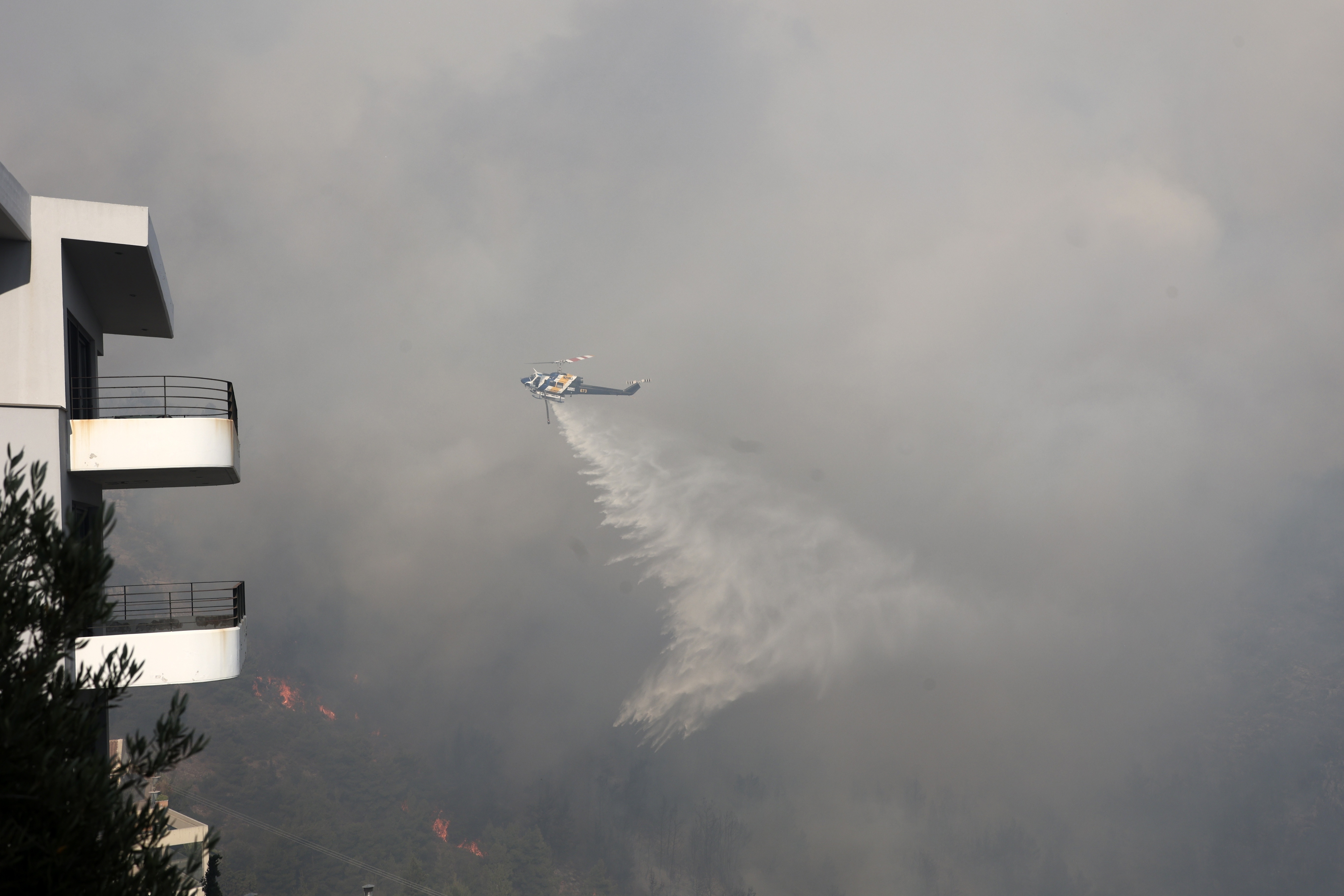 An helicopter drops water over a wildfire in Voula suburb, in southern Athens, Greece, Saturday, June 4, 2022. (AP Photo/Yorgos Karahalis)