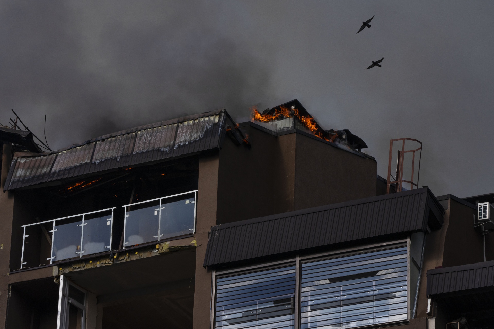 Birds fly over a residential building following explosions, in Kyiv, Ukraine, Sunday, June 26, 2022. Several explosions rocked the west of the Ukrainian capital in the early hours of Sunday morning, with at least two residential buildings struck, according to Kyiv mayor Vitali Klitschko. (AP Photo/Nariman El-Mofty)
