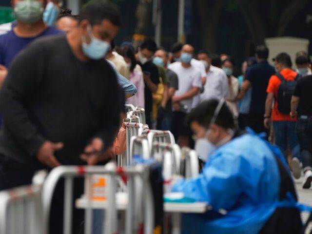 Office workers and residents line up along a street for their throat swab at a coronavirus