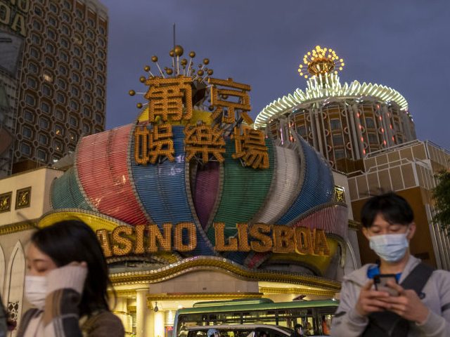 Pedestrians wearing face masks pass the Casino Lisboa, operated by SJM Holdings Ltd., after its lights were switched off at dusk in Macau, China, on Wednesday, Feb. 5, 2020. Casinos in Macau, the Chinese territory that's the world's biggest gambling hub, closed for 15 days as China tries to contain …