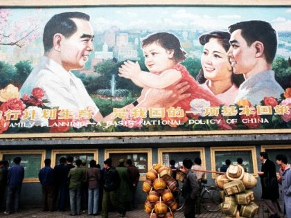 Pedestrians and a man carrying baskets pass by a huge billboard extolling the virtues of China's "One Child Family" policy.. (Photo by Peter Charlesworth/LightRocket via Getty Images)