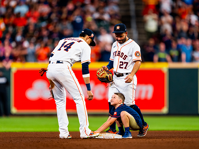 Astros fan Oliver, 6, steals second base with help from players Jose Altuve and Mauricio D