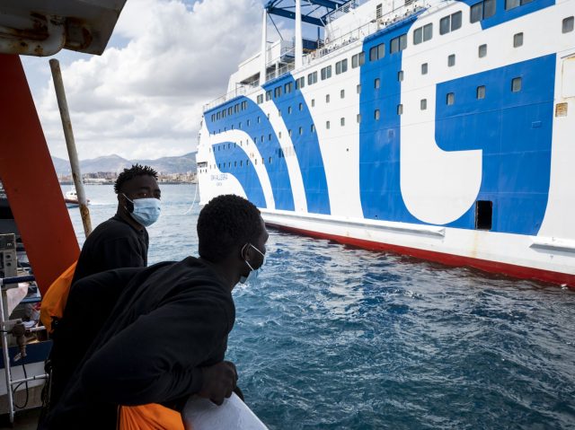 Two migrants ob board the Sea-Watch 4 civil sea rescue ship look on as they approach a ferry at sea off the coast of Palermo, Sicily, Italy, on September 02, 2020, in order to disembark some 350 migrants who will be under quarantine. - More than 350 migrants including those …