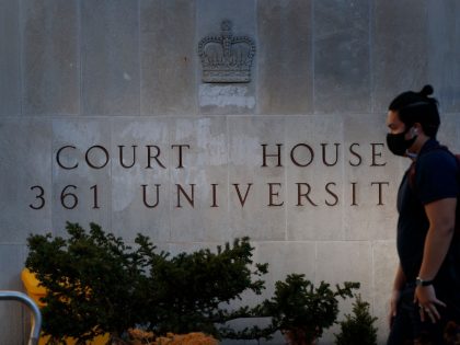A man walks by the engraved signage outside the Superior Court of Justice in Toronto, Ontario, Canada on November 10, 2020, during the first day of the trial for accused van attacker Alek Minassian. - A Canadian man linked to the misogynist "incel" movement and accused of killing 10 people …