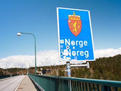 A street sign is seen reading "Norway" in both Norwegian and Swedish languages on the old bridge of Svinesund, Sweden, on May 1, 2021. - They haven't been allowed to have each other over for a year because of Covid. So come rain or shine, two 73-year-old Swedish twins have …