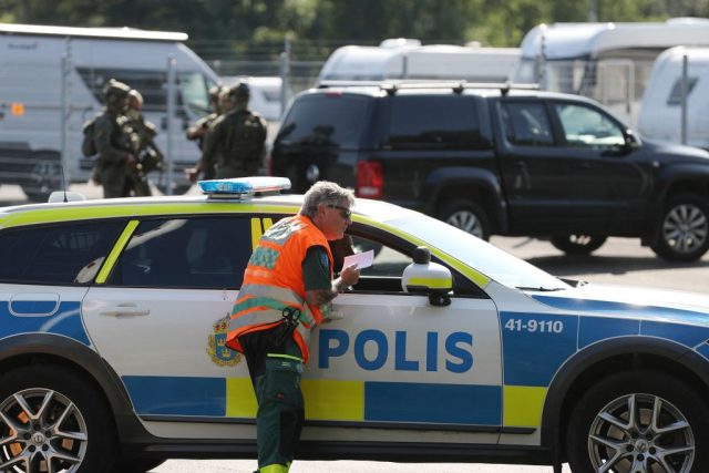 A medical personnel leans over the window of a police vehicle as special unit police forces stand by a car parked outside the Hallby Prison near Eskilstuna, Sweden, on July 21, 2021. - A large police operation is underway on July 21, 2021 as two inmates imprisoned for murder have …