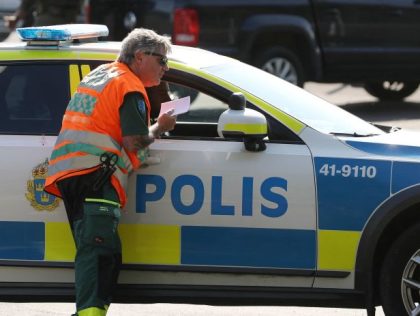 A medical personnel leans over the window of a police vehicle as special unit police forces stand by a car parked outside the Hallby Prison near Eskilstuna, Sweden, on July 21, 2021. - A large police operation is underway on July 21, 2021 as two inmates imprisoned for murder have …