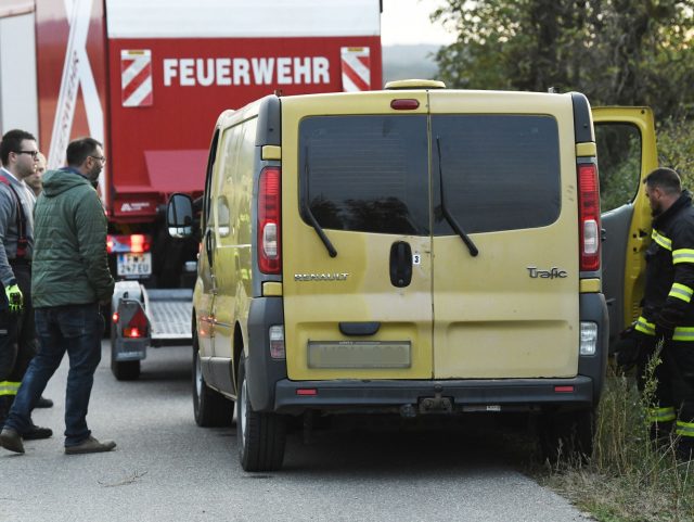 Austrian firemen inspect the van where two migrants were discovered dead during a control