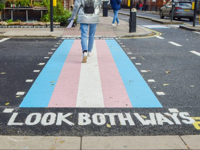 LONDON, UNITED KINGDOM - 2021/11/09: A woman walks along a pedestrian crossing with trans