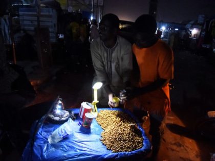 A roadside vendor sells Tigernuts lit up with torchlight at a market without electricity at Ibafo, Ogun State southwest Nigeria, on March 22, 2022. - Blackouts are common in Africa's top petroleum producer, where dilapidated infrastructure often fails to distribute even insufficient electricity supplies. But extended collapses of the power …